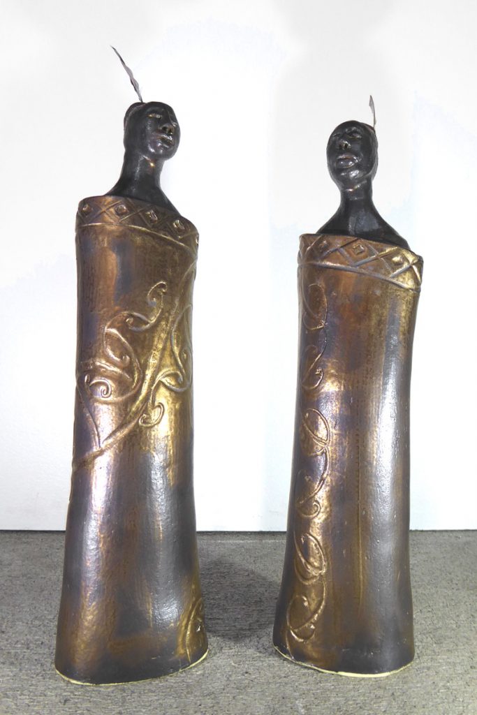 Ceramic figures of maori wearing cloaks by Fiona Bryant