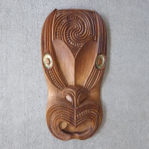 Carved wooden face with paua eyes by Teraiman Tahiata